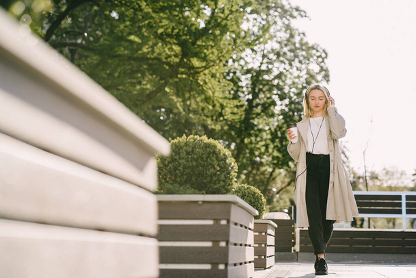 Blonde walks in summer city with cup of coffee - Фото, зображення