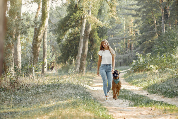 Girl in a summer forest playing with dog - Foto, afbeelding