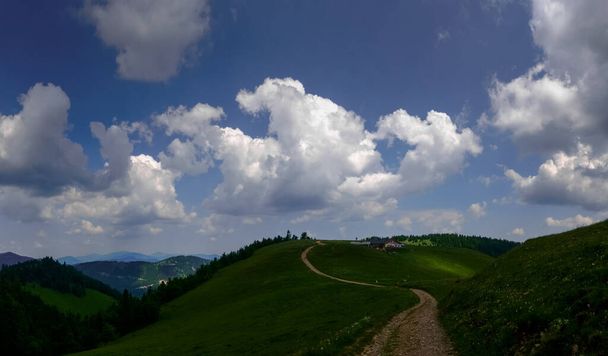 lange bochtige pad op een prachtige groene heuvel in een berglandschap panorama uitzicht - Foto, afbeelding
