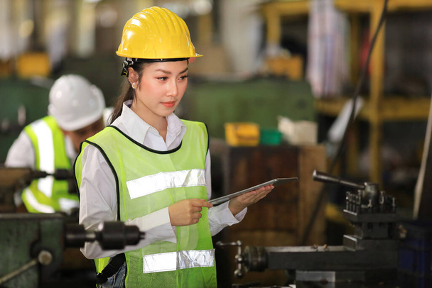 完全な安全装置の女性エンジニアは、デジタルタブレットを使用して重工業工場内で作業や検査を行っています。 - 写真・画像