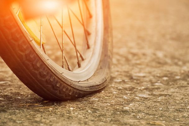 Nahaufnahme des Fahrrads, das einen platten Reifen hat und auf dem Bürgersteig geparkt ist, verschwommener Hintergrund. Weiche und selektive Fokussierung auf Reifen. - Foto, Bild
