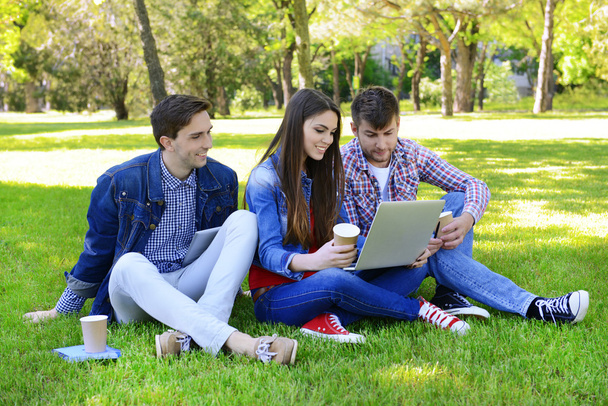 Happy students sitting in park - Photo, Image