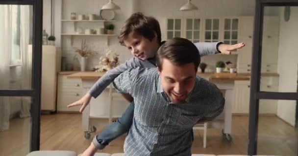 Active young father carrying on back laughing son. - Materiaali, video