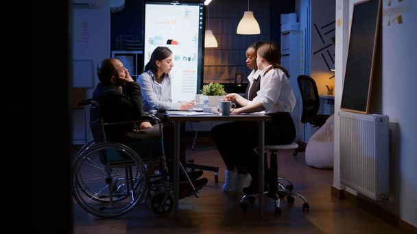 Перегруженный работой бизнесмен-инвалид в инвалидной коляске игнорируется во время работы в офисе компании - Фото, изображение