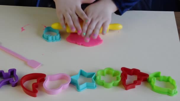 Mãos de menina 3-5 anos de idade jogando massa de jogo rosa com moldes de plástico - Filmagem, Vídeo