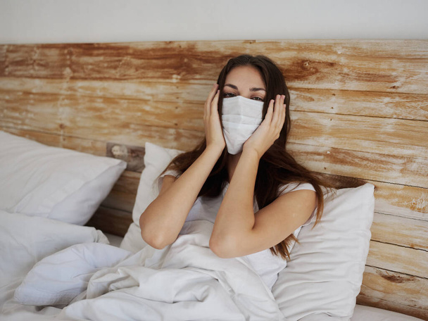 egy nő orvosi maszkban fekszik az ágyban egy párnán pandémiás karantén koronavírus tüdőbetegség - Fotó, kép