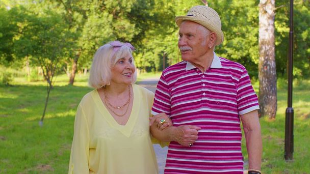 Старшие старые стильные туристы пара бабушка, дедушка, гуляющий и разговаривающий в летнем парке - Фото, изображение