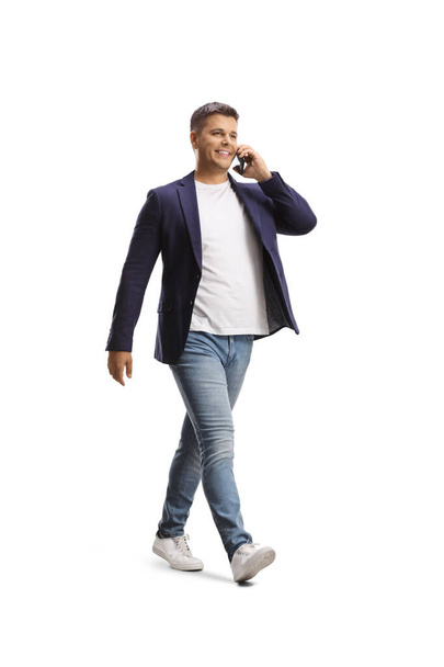 Full length shot of a casual man walking and using a smartphone isolated on white background - Foto, afbeelding