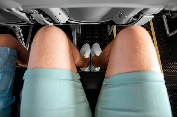 Feet close-up in the aircraft cabin, fear of flying, the cabin of a passenger airliner. Aerophobia, phobia, international flights, stress, motion sickness - Zdjęcie, obraz