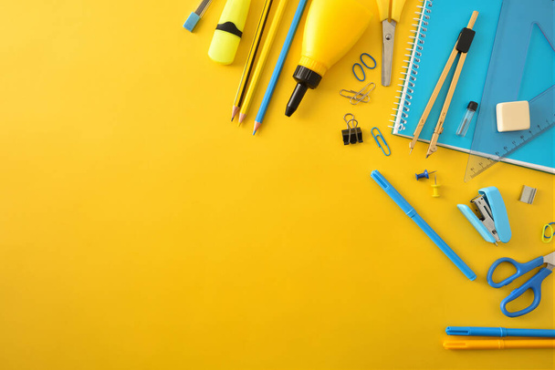 Yellow and blue school supplies on yellow background and top empty space. Top view. Diagonal composition. - Photo, image