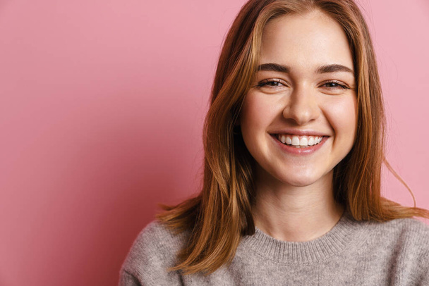 Young ginger happy woman smiling and looking at camera isolated over pink background - Foto, immagini