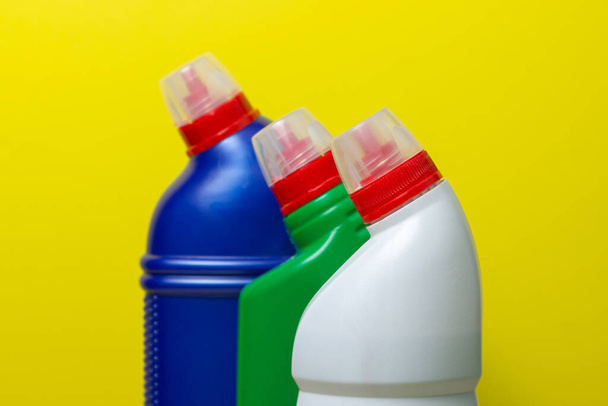 Huishoudelijke chemicaliën op een gele achtergrond. Schoonmaakmiddelen voor huishoudelijk gebruik. - Foto, afbeelding