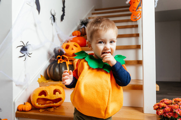 Cute smiling baby dressed as pumpkin looking at camera - 写真・画像