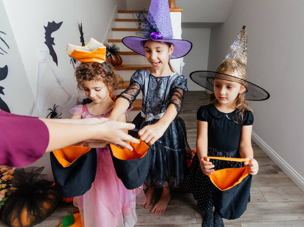 Girls receiving bunch of candies during halloween trick or treating - Фото, зображення