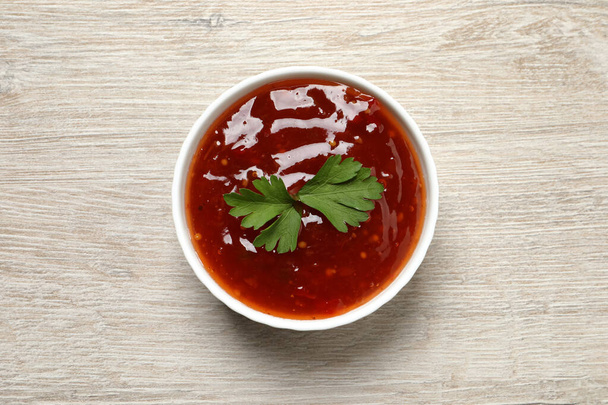 Spicy chili sauce with parsley in bowl on white wooden table, top view - Fotografie, Obrázek