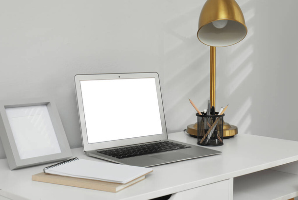 Kényelmes munkahely modern laptoppal a világosszürke fal közelében. Tervezési hely - Fotó, kép