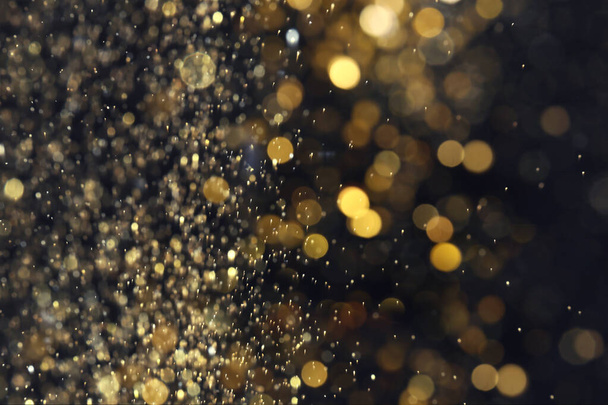Blurred view of golden lights on black background. Bokeh effect - Φωτογραφία, εικόνα