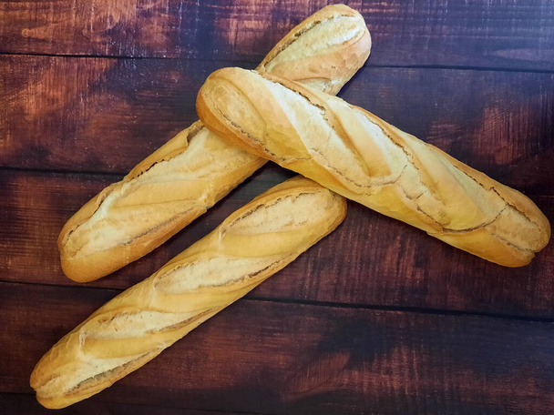 Świeżo upieczony chleb na drewnianym blatze gotowy do sprzedaży - Zdjęcie, obraz
