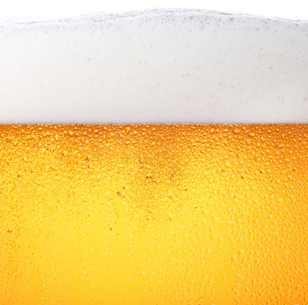 Gros plan texture de fond de verser de la bière blonde avec des bulles et de la mousse en verre givré avec des gouttes, vue latérale à angle bas - Photo, image