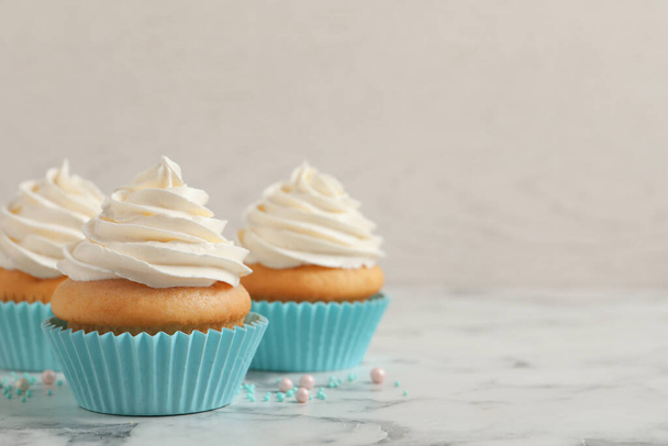 Delicious cupcakes decorated with cream on white marble table, space for text - Fotoğraf, Görsel