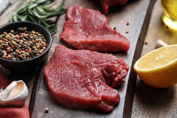 Fresh raw meat steaks and spices on wooden table, closeup - Photo, Image
