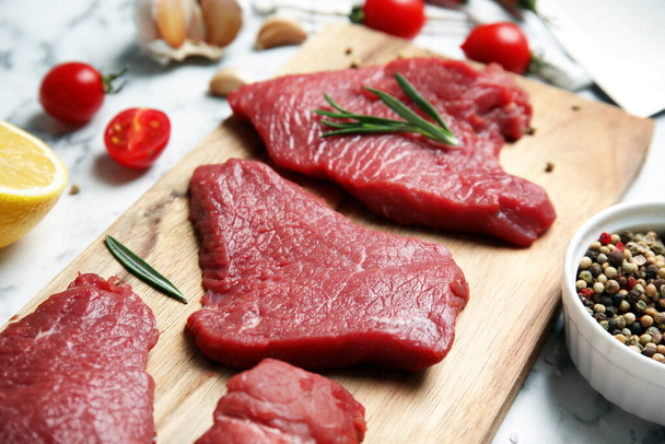 Fresh raw meat steaks and spices on white table, closeup - Фото, изображение