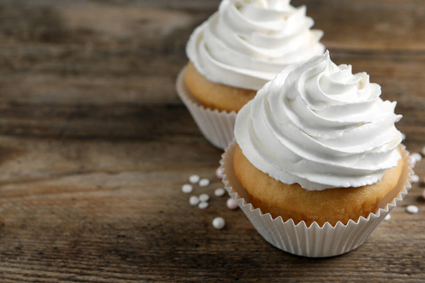 Delicious cupcakes with cream on wooden table, closeup. Space for text - Foto, Imagem
