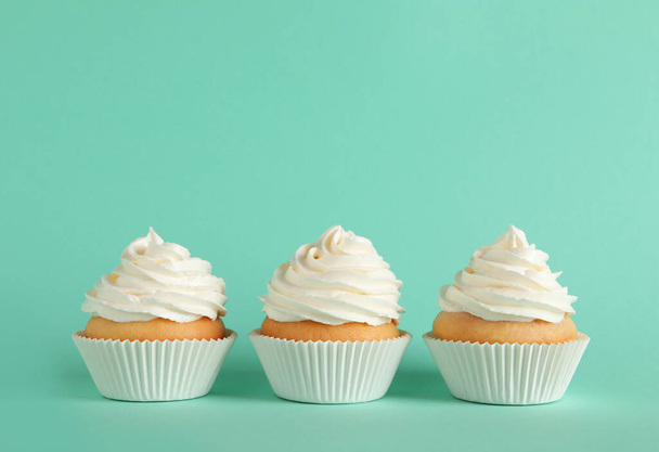 Delicious cupcakes with white cream on turquoise background. Space for text - Foto, Imagem