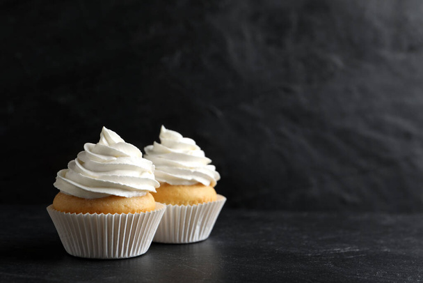 Delicious cupcakes with cream on black table. Space for text - Fotoğraf, Görsel