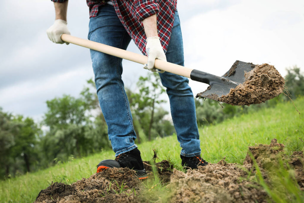Worker digging soil with shovel outdoors, closeup - Photo, Image