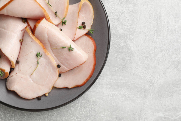 Delicious cut ham with thyme and peppercorns on light grey table, top view. Space for text - Φωτογραφία, εικόνα