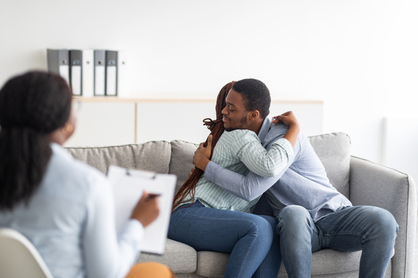 Glückliches schwarzes Paar umarmt sich nach erfolgreicher Ehetherapie in Beratungsstelle - Foto, Bild