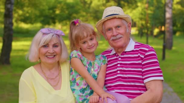 Nieta pequeña junto con la abuela mayor y el abuelo en el parque, relación familiar - Imágenes, Vídeo