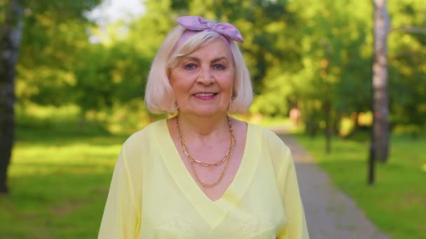 Neşeli, sevimli, yaşlı, kır saçlı, yaz parkının arka planında günlük sarı bluz giyen büyükanne. - Video, Çekim