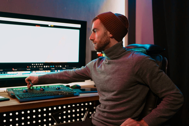 Hombre editor de vídeo Trabajando en su ordenador personal con pantalla grande en blanco - Foto, Imagen