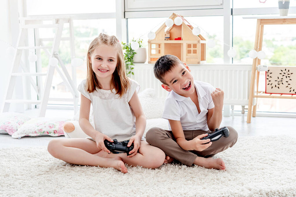 Little girl and boy playing on console - Foto, afbeelding