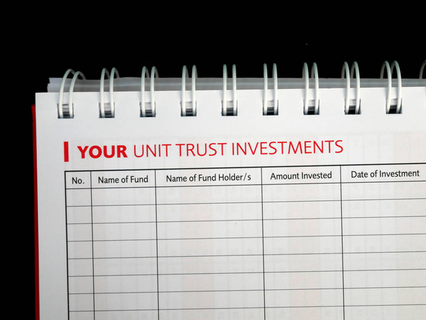 Kiválasztott összpontosított Unit Trust Befektetési szöveg található az egyik oldalon a notebook. Legyen a címe egy befektetési alapokat tartalmazó táblázatnak, amely még mindig üres.. - Fotó, kép