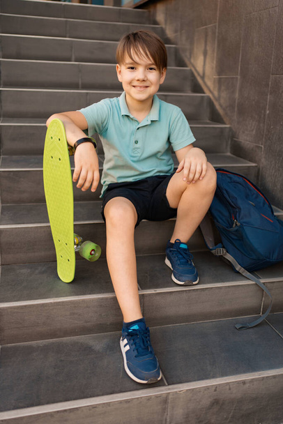 Chlapec sedí na schodech s batohem a penny - Fotografie, Obrázek