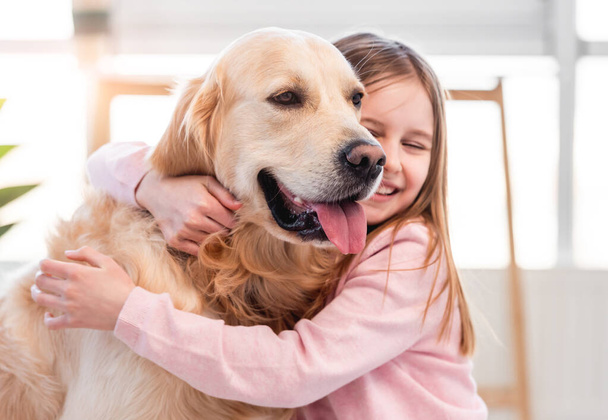 Little girl petting golden retriever dog - Fotó, kép