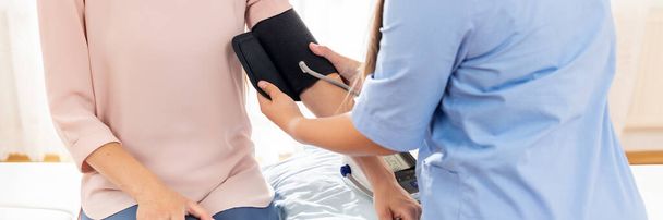 Young woman having her blood pressure checked by a nurse, doctor or a health visitor. Heart health banner. Blood pressure digital gauge monitor. - Фото, зображення