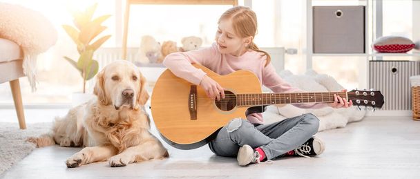 Little girl with guitar and golden retriever dog - Photo, Image