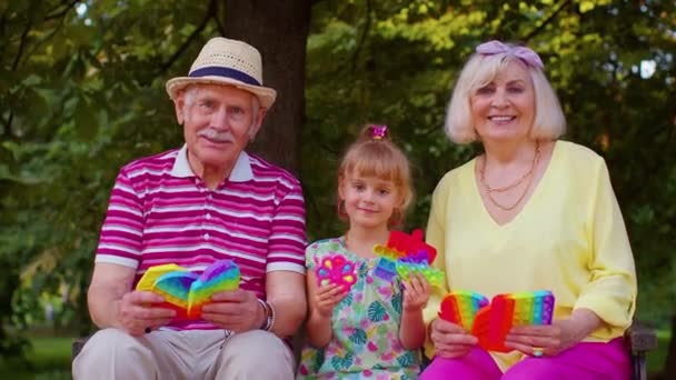 Старший дедушка бабушки с внучкой проведение антистрессовых поп-это игрушки игры в парке - Кадры, видео