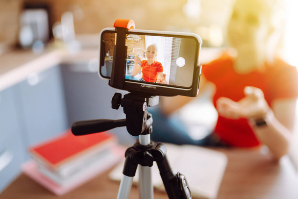 Young woman recording her video blog. Woman blogger videotapes her vlog at home. Vlogger makes online streaming using phone. Social media, instagram, stay home and quarantine. - Fotó, kép