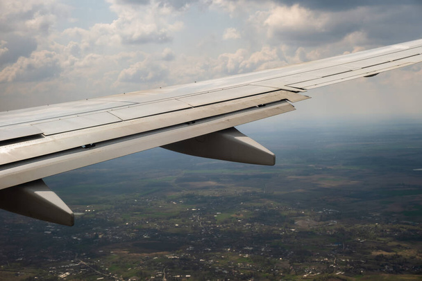 Vista del ala del avión a reacción aterrizando en el aeropuerto con mal tiempo. Concepto de viaje y transporte aéreo. - Foto, imagen