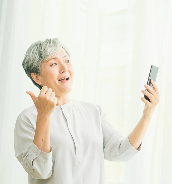 Senior mujer asiática usando o hablando en su teléfono móvil. - Foto, imagen