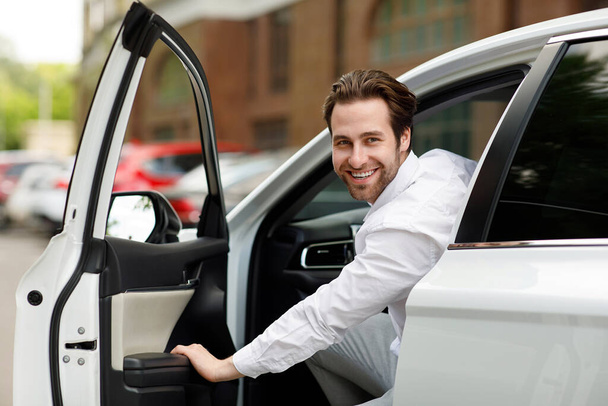Geweldige aanbieding, zakenman kopen auto zitten in de bestuurdersstoel, het testen van auto in dealerovereenkomst showroom - Foto, afbeelding