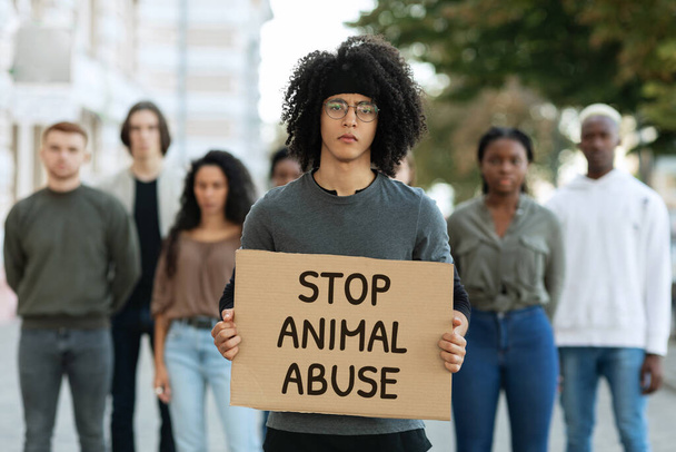 Чорний хлопець тримає плакат зупинити жорстоке поводження з тваринами
 - Фото, зображення
