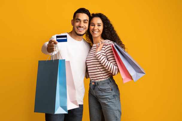 Retrato de feliz pareja de Oriente Medio con tarjeta de crédito y bolsas de compras - Foto, imagen