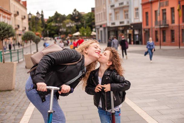 The daughter kisses mom while riding a scooters - Fotografie, Obrázek