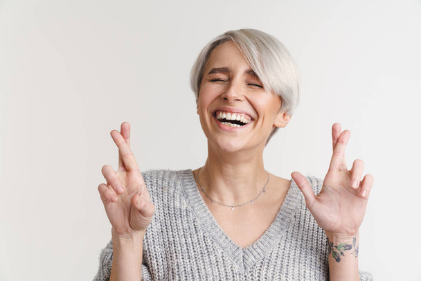 White-haired young woman laughing while holding fingers crossed isolated over white wall - Foto, Imagem